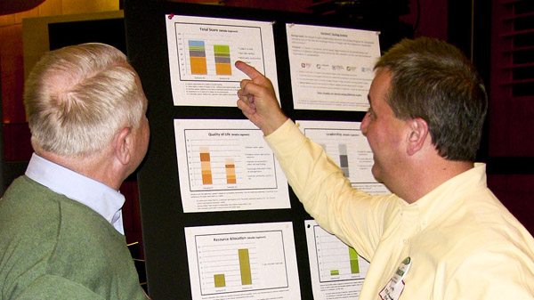 At a public meeting, two attendees compare Envision™ scores of potential project scenarios. 